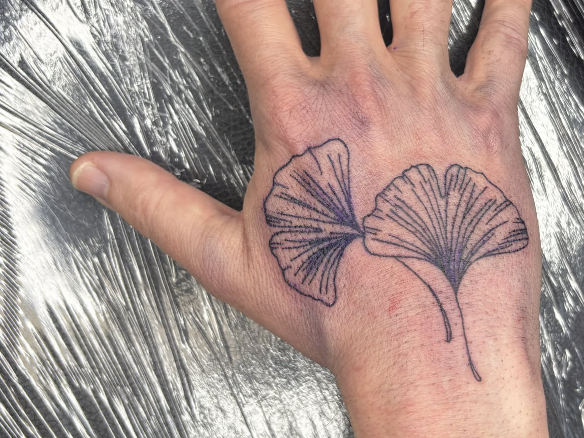 Frisches Tattoo zweier Gingkoblätter auf einem Handrücken