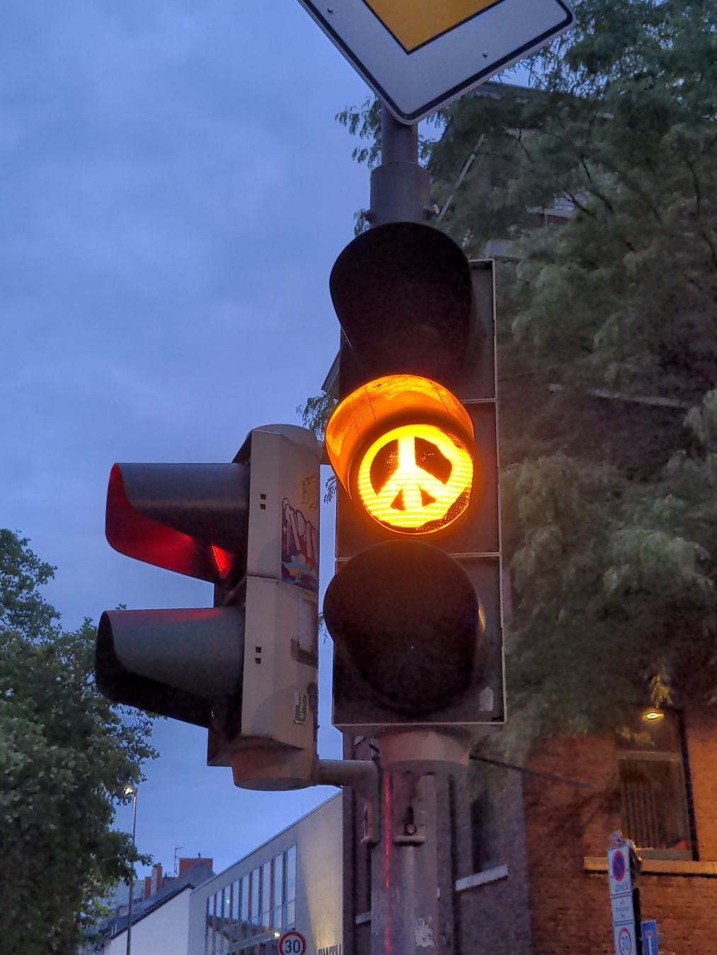 Eine Ampel, das Gelb zeigt das Peace Zeichen.